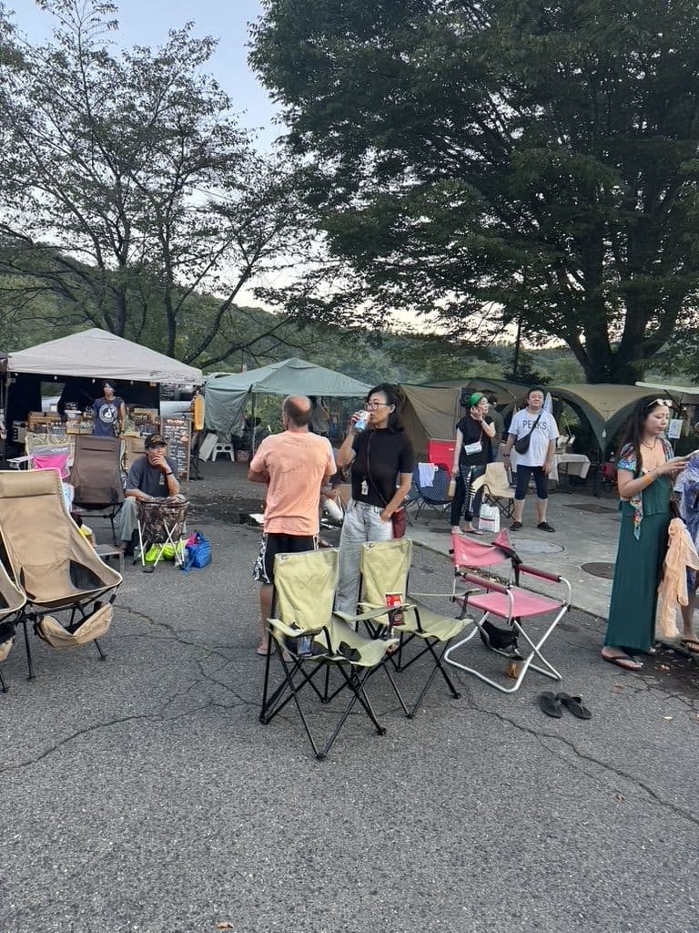 駐車場に並ぶテントと椅子。昼の会場でくつろぐ人たち